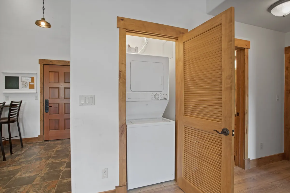 A practical and inviting in-unit laundry space with a washer and dryer tucked into a cozy nook. Warm wooden accents and a clean layout add to the sense of convenience and comfort.