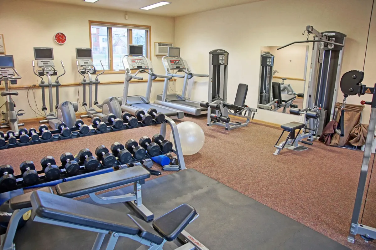 A bright, well-equipped fitness center with a rack of dumbbells, treadmills, and various workout stations. The space is modern and energetic, with ample natural light inviting guests to enjoy a vigorous workout.